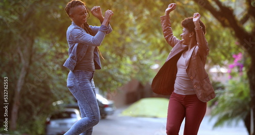 Two women celebrating news outside dancing. African black ethncity friends dance photo