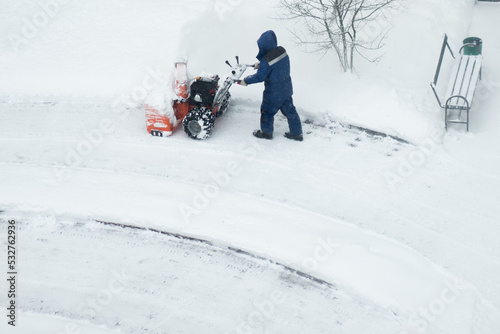 snowblower removes snow, a man cleans the yard outside