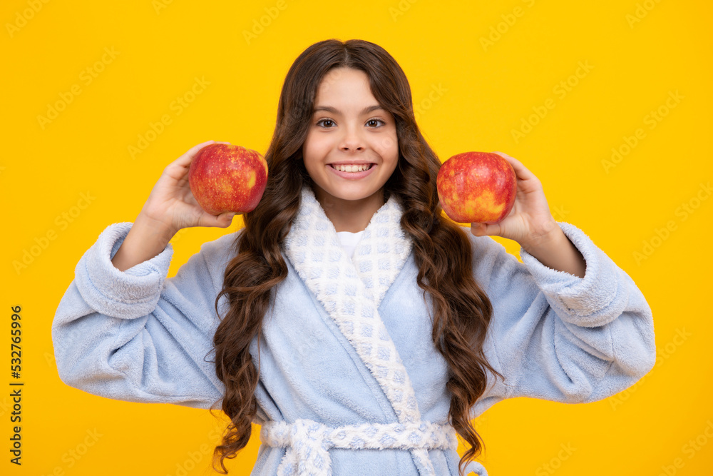 Child girl eating an apple over isolated yellow studio background. Tennager with fruit. Portrait of happy funny smiling teenage child girl. Child girl eating an apple over isolated yellow studio background. Tennager with fruit. Portrait of happy funny smiling teenage child girl.