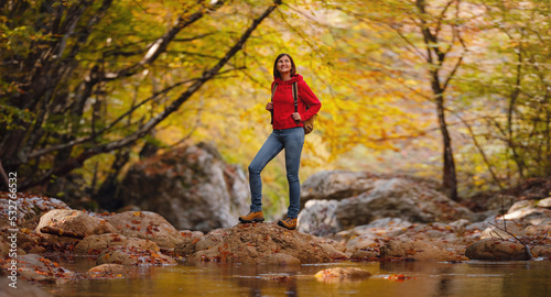 Travel and road trip concept at autumn. Adventure and active lifestyle in nature. Tourist hiking in forest. Asian woman in red hoodie walks in forest. Wanderlust concept.