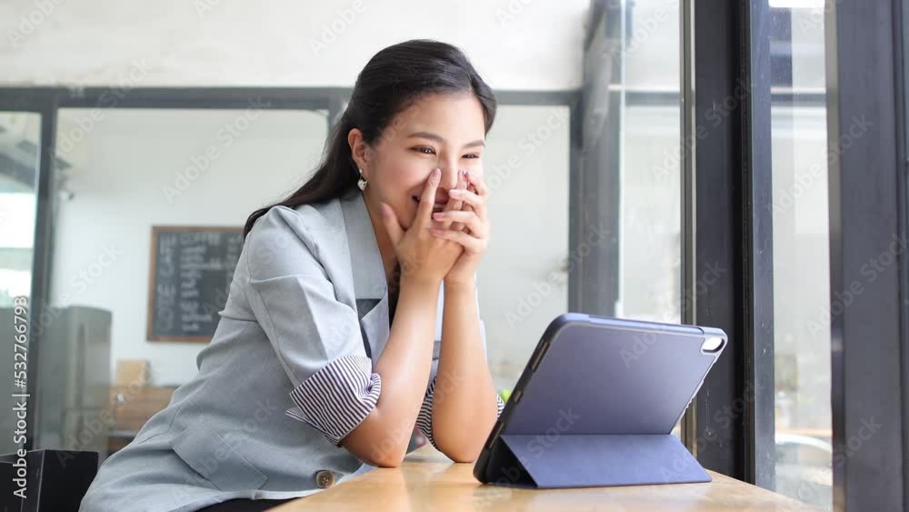 Happy smiling Asian woman watching movie using digital tablet on vacation at cafe. Happy smiling Asian woman watching movie using digital tablet on vacation at cafe.