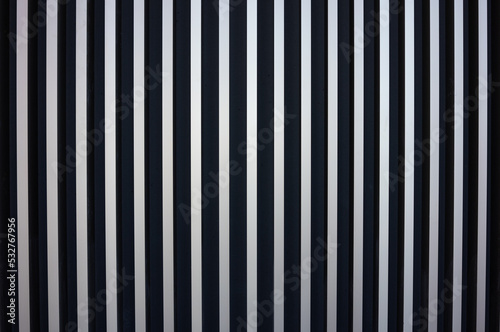 Texture of a wall of metal strips. vertical stripes alternating metal to black. Clear texture as a graphic, design background. Simple pattern with lots of copy space.