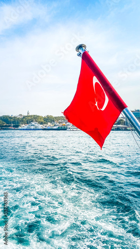Istanbul, Turkey, OIctober 11, 2021. View of a ferry boat, historical mosques in Eminonu area and many people in Istanbul. It is a sunny summer day. Turkish flag waving on the ferry.