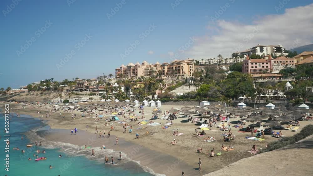 Beautiful beach with people on tenerife island at sunny summer day, luxury touristic resort with boutique hotel on the island in sea. High quality FullHD footage Beautiful beach with people on tenerife island at sunny summer day, luxury touristic resort with boutique hotel on the island in sea. High quality FullHD footage