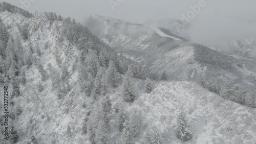 Aerial tilt down on white snowy mountain valley in winter in Aspen Colorado on snowy grey day