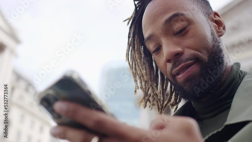 Close shot of handsome man reacting positively to something on his phone outdoors in the city
