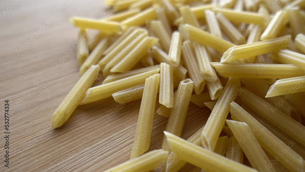 Raw italian penne rigate pasta isolated on wooden background Raw italian penne rigate pasta isolated on wooden background