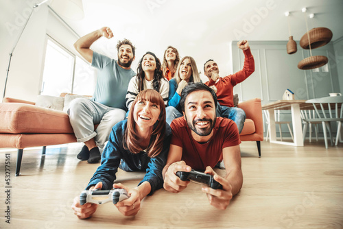 Happy friends playing together video game at home - Group of young people having fun sitting on the couch looking television - Modern technology and friendship concept