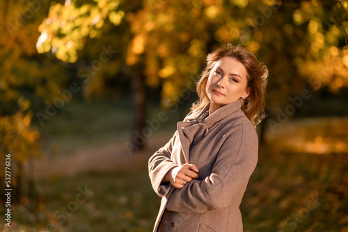 Portrait of a woman in a warm coat on the background of autumn golden leaves
