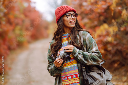 Young woman- tourist taking pictures in the autumn forest.  Rest  relaxation  tourism  nature  lifestyle concept.