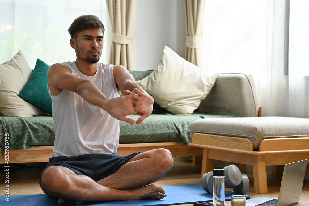 Handsome Young Asian man doing arm stretching exercise at home.