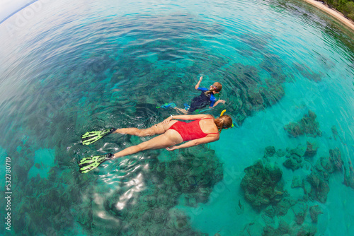 Happy family - mother, kid in snorkeling mask dive underwater, explore tropical fishes in coral reef sea pool. Travel active lifestyle, beach adventure, swimming activity on summer holiday with child.