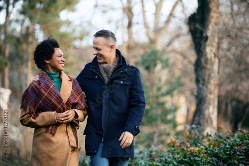 Happy multiracial couple enjoys in walk during winter day at park. © Drazen