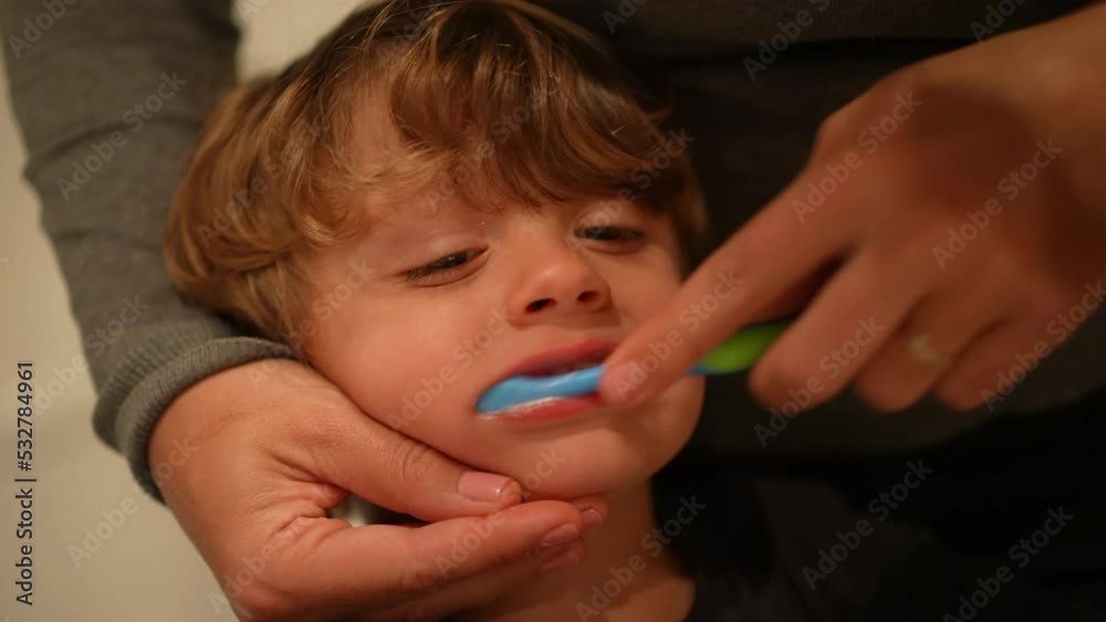 Mother brushing teeth with toothbrush. Closeup small boy mouth and face brushes tooth Mother brushing teeth with toothbrush. Closeup small boy mouth and face brushes tooth