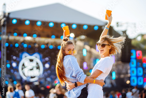 Canvas Print Two female friends drink beer and have fun at the music festival