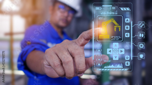 An engineer is working in an industrial facility with a holographic screen showing automated controls in front of him.