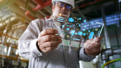 Engineers are inspecting manufacturing processes, reading holographic screens showing various piping and control systems within the plant. photo