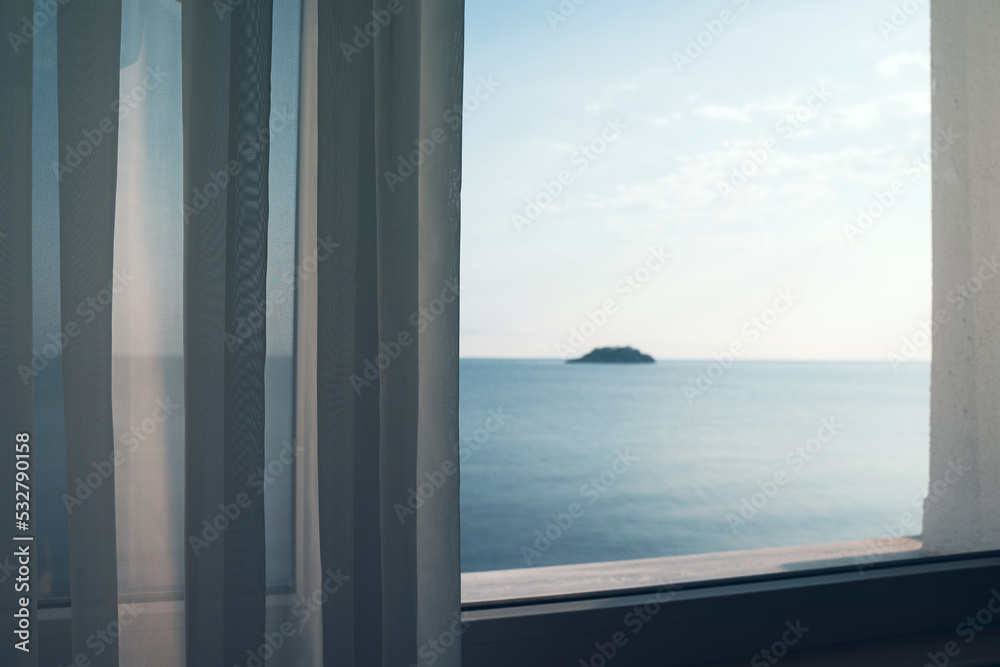 Fototapeta premium small ocean island seen through a window with transparent fabric curtains