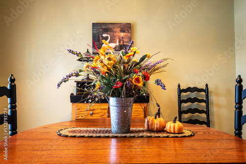 dinning room decorated for fall with flower bouquet centerpiece and pumpkins on oak table photo