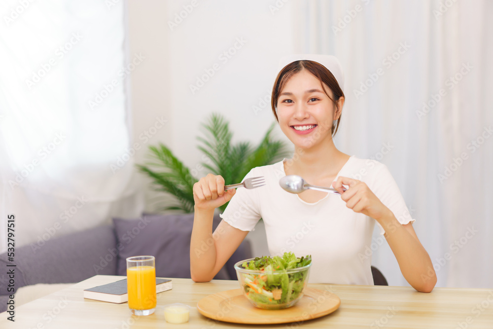 Lifestyle in living room concept, Young Asian woman eating vegetable salad and orange juice Lifestyle in living room concept, Young Asian woman eating vegetable salad and orange juice