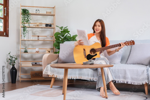 Concept of relaxation with music, Young woman reading lyrics and playing music with acoustic guitar