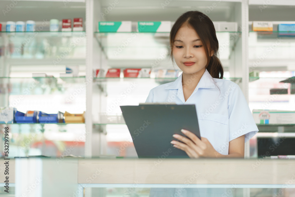 Medicine and health concept, Female pharmacist is checking stock medicine on clipboard in pharmacy