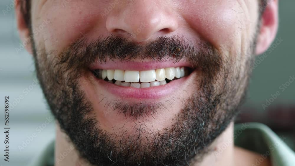Selective focus on the lips of a handsome confident Caucasian bearded man, smiling a cheerful toothy smile standing forward to camera. White teeth, oral care, dental hygiene, teeth whitening concept Selective focus on the lips of a handsome confident Caucasian bearded man, smiling a cheerful toothy smile standing forward to camera. White teeth, oral care, dental hygiene, teeth whitening concept