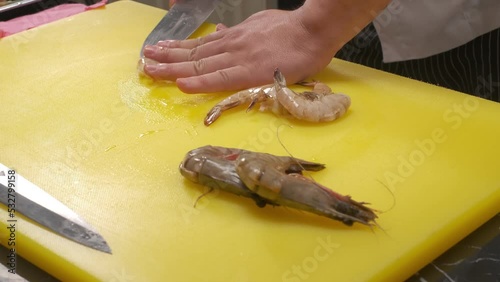 The chef cuts srimps on a board with a knife photo