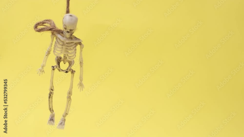 skeleton hanging on gallows over yellow background. Halloween video