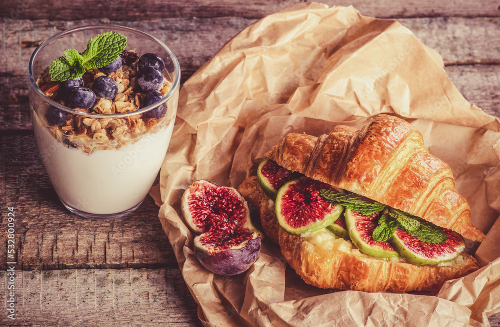 Delicious beautiful breakfast. Croissant with figs and yogurt with berries