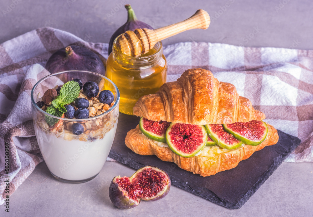 Homemade yogurt with berries and a croissant with figs. Nice healthy breakfast