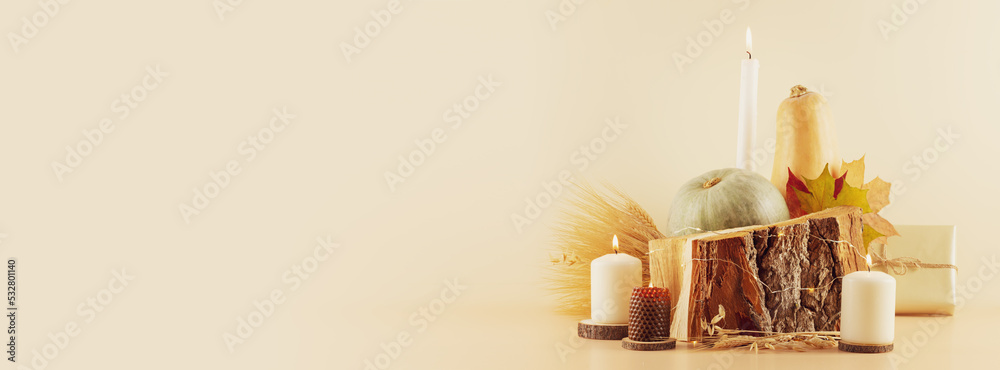 Thanksgiving holiday banner with pumpkins, dry autumn leaves, bouquet of rye and wheat ears, gifts and candles on a wooden podium on a beige background with copy space. Happy Thanksgiving Day Thanksgiving holiday banner with pumpkins, dry autumn leaves, bouquet of rye and wheat ears, gifts and candles on a wooden podium on a beige background with copy space. Happy Thanksgiving Day