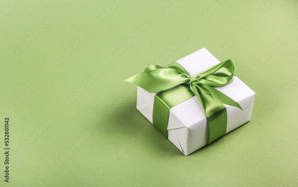 White gift box with green bow on green background. Gift box copy space