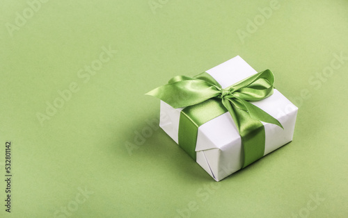 Obraz na płótnie White gift box with green bow on green background. Gift box copy space w salonie