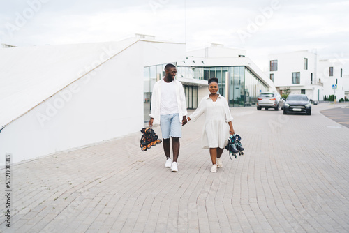 Obraz na płótnie Black couple with inline skates on sidewalk