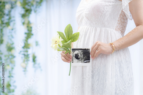 マタニティドレスでエコー写真を持つ妊婦 室内（本物の臨月妊婦さんを撮影） photo