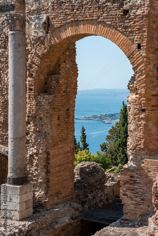 Mediterranean sea seen from arch at old ruins of ancient Greek theater at coastal city. Historic building structure at Giardini Naxos bay in summer. View of famous tourist attraction on sunny day.