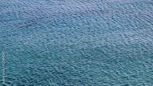 Genova, Italy- July 27, 2022:Panorama of the blue sea, light above the water, ocean sunrise. Some little waves in winter days. Clear sky reflected on the water.