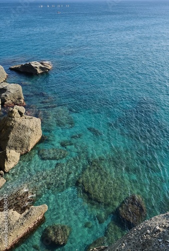 Genova, Italy- July 27, 2022:Panorama of the blue sea, light above the water, ocean sunrise. Some little waves in winter days. Clear sky reflected on the water.