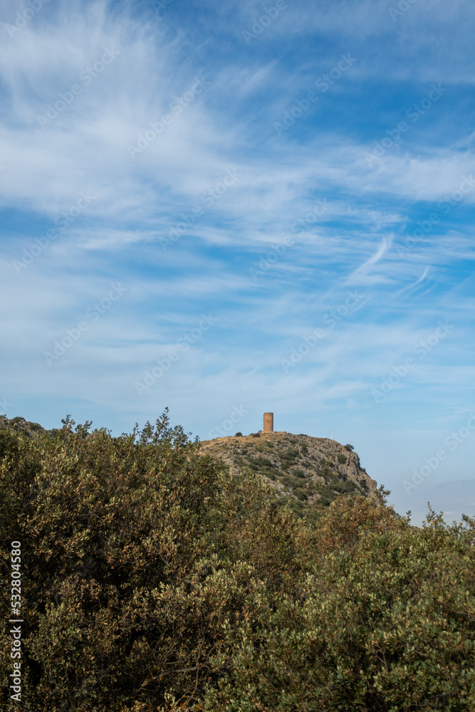 Atalaya de Deifontes (Spain) on a rocky hill surrounded by oaks on a sunny summer morning