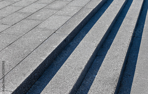 Gray steps of gray paving slabs. Gray concrete or stone stairs steps background. Abstract stairs, abstract steps, city stairs. Light and shadow on the stone steps. Black and white photography,diagonal