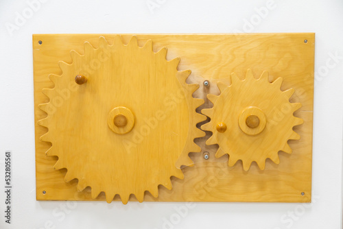 Wooden cogwheel toy on white wall photo