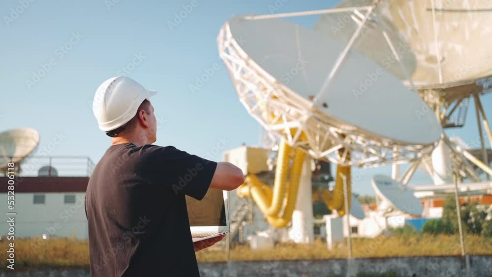 Engineer testing earth based astronomical radio telescope use laptop