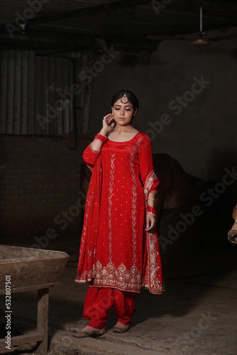 girl with long hair wearing red suit standing with cow