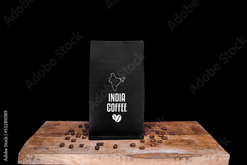 India coffee beans and black package on wooden board with black isolated background