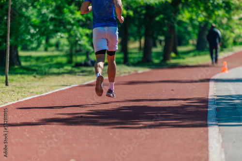 Rearview of a young athlete running outdoors on the race track
