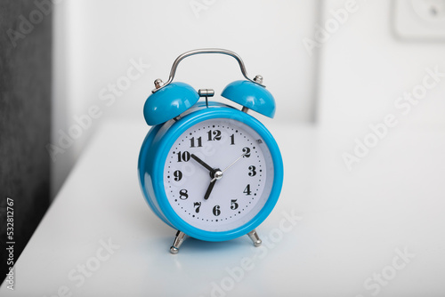 Close up photo of alarm clock standing on nightstand in the bedroom at the morning time