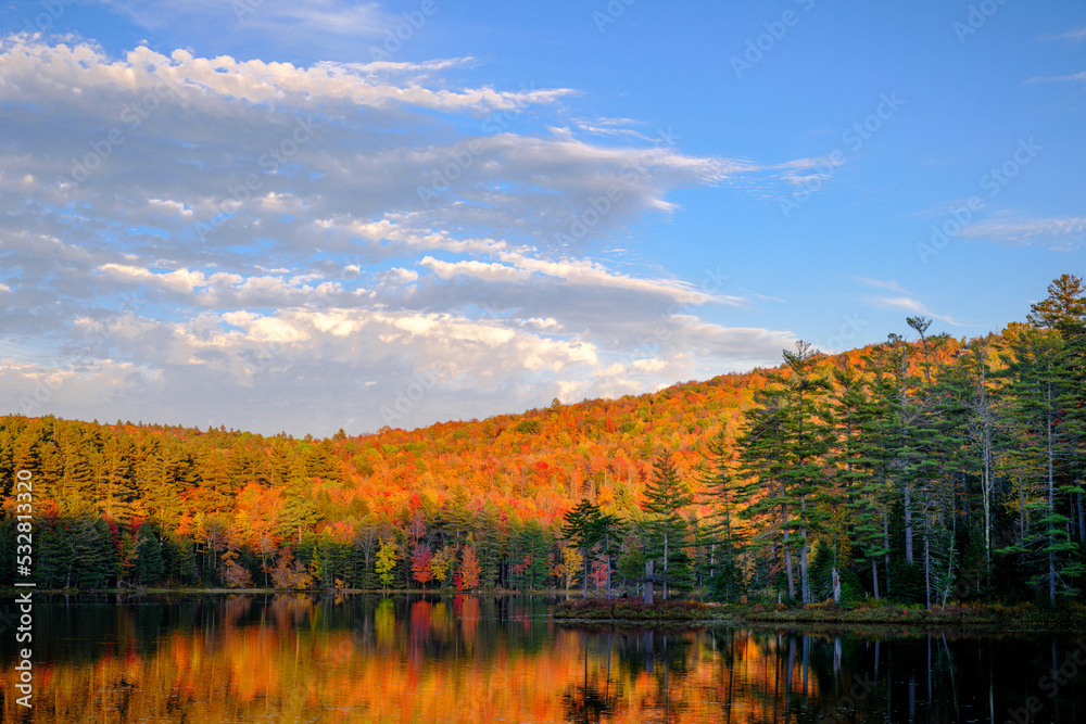 A beautiful autumn scene in the late afternoon with a colorful forest, lake, and reflections on the water
