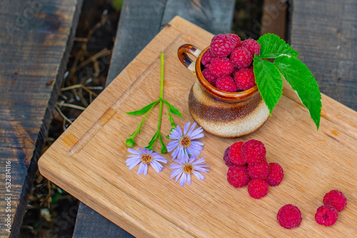 raspberries in a glass and a handful of raspberries and flowers of the Novobelgian Aster. High quality photo photo