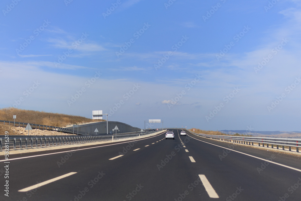 Fototapeta premium Highway wide road, transport and blue sky with clouds on a summer day